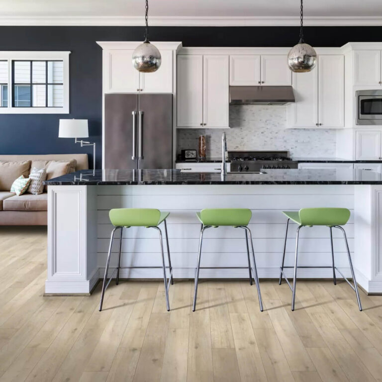Kitchen island with black hard stone counter and white cabinets with lime green stools