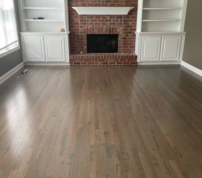 living room with a classic red brick fireplace, with built-in shelves and hardwood floors