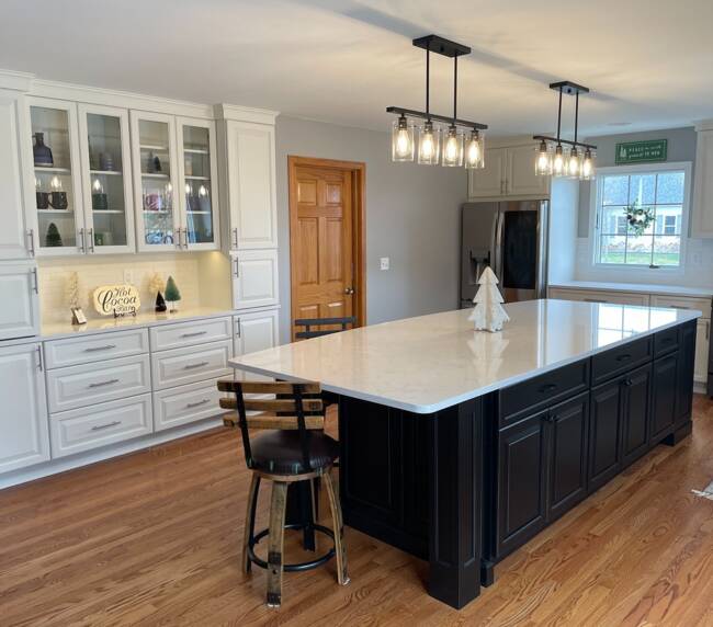 kitchen with a large black island, wooden flooring, and white countertops