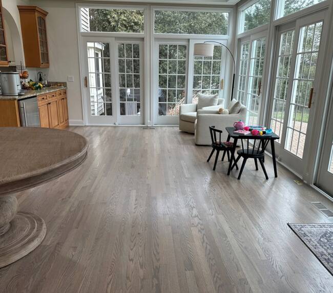 living area with large windows, cozy seating, a charming play corner, and beautiful hardwood flooring