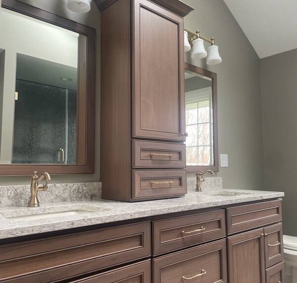 Bathroom vanity with rich wooden cabinets, marble countertop, and gold fixtures