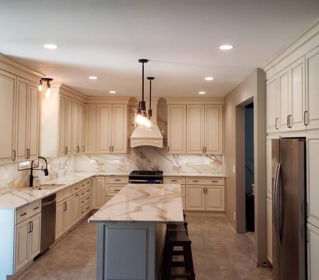 kitchen featuring beige cabinetry, marble countertops, and backsplash