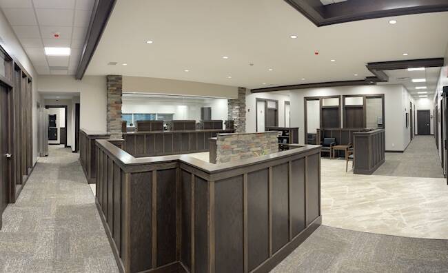office area with dark wood paneling, stone accents, beige floor tiles, and grey carpet flooring
