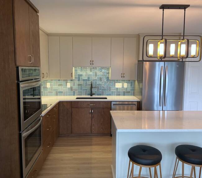 kitchen with a mix of wood and grey cabinets, blue tile backsplash, and white countertops