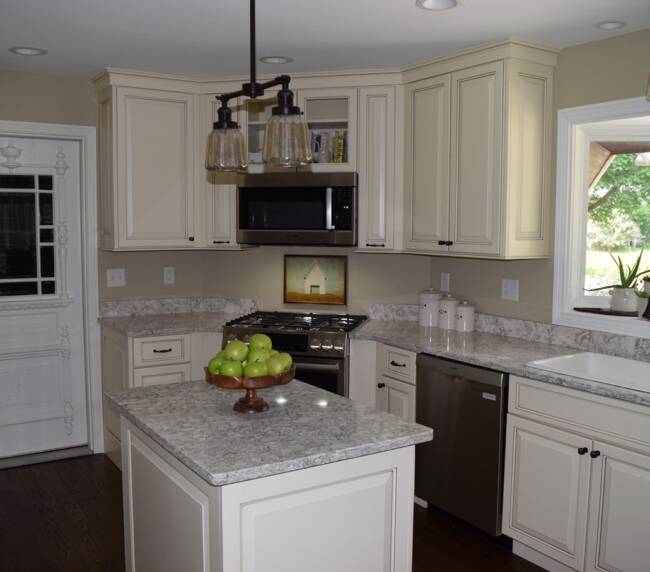 kitchen with cream-colored cabinets, granite countertops, a central island, and vintage pendant lighting