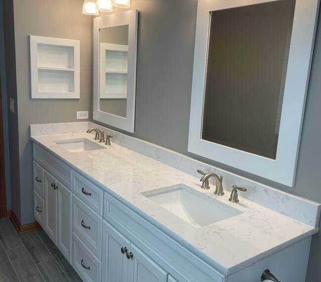 Bathroom with a double vanity featuring a white marble countertop and gray wood-look tile flooring