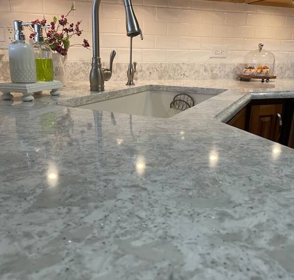 kitchen sink area with a polished quartz countertop and subway tile backsplash