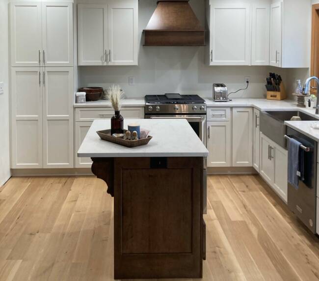 Kitchen with white shaker cabinets, a dark wood island, and a light wood floor
