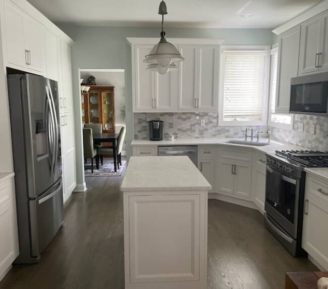 kitchen with white cabinets, grey countertops, hexagonal tile backsplash, stainless steel appliances, and a central island